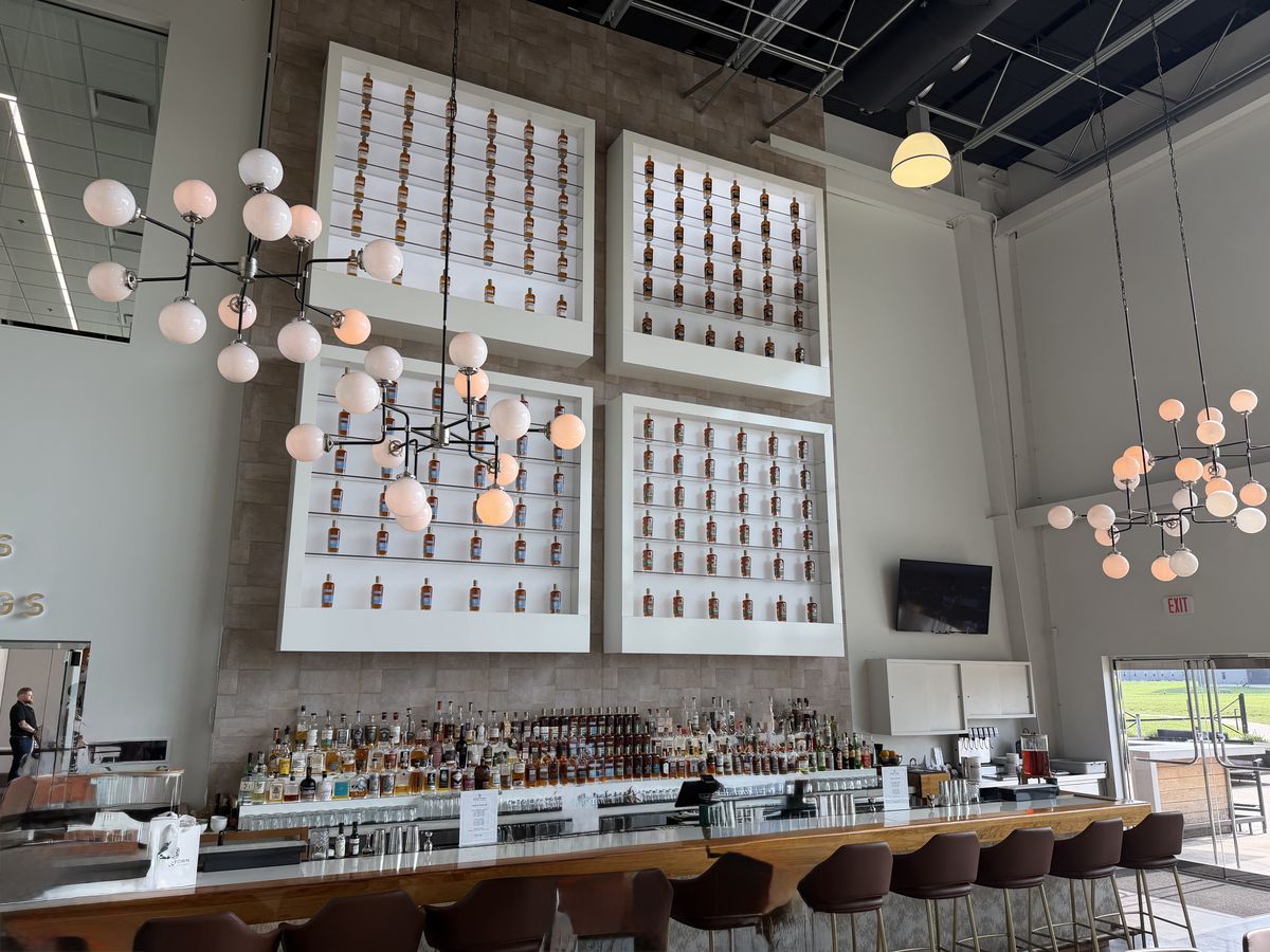 Bardstown Bourbon Company bar with a backlit wall of bottles behind it
