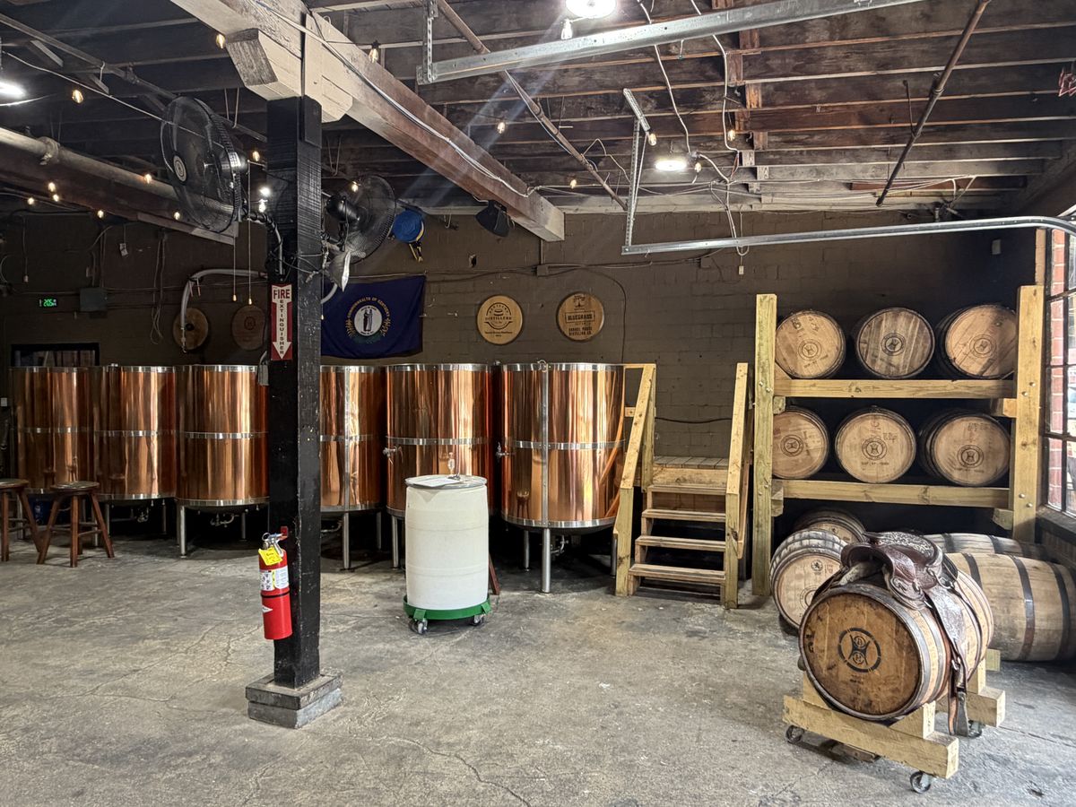 Copper pot stills and stacked barrels on the Barrel House production floor