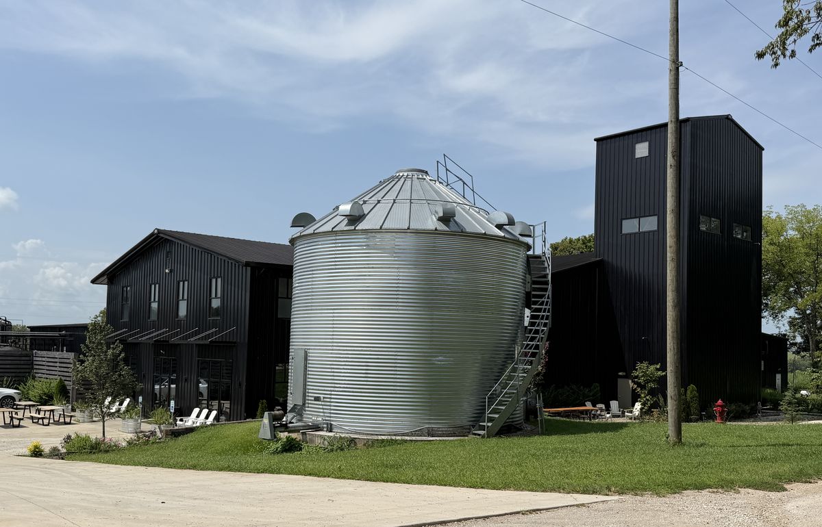 Bluegrass Distillers farm campus with black barn buildings and a grain silo