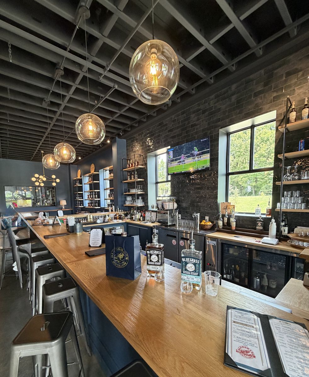 Bluegrass Distillers bar with globe pendant lights and bottle shelves along a brick wall