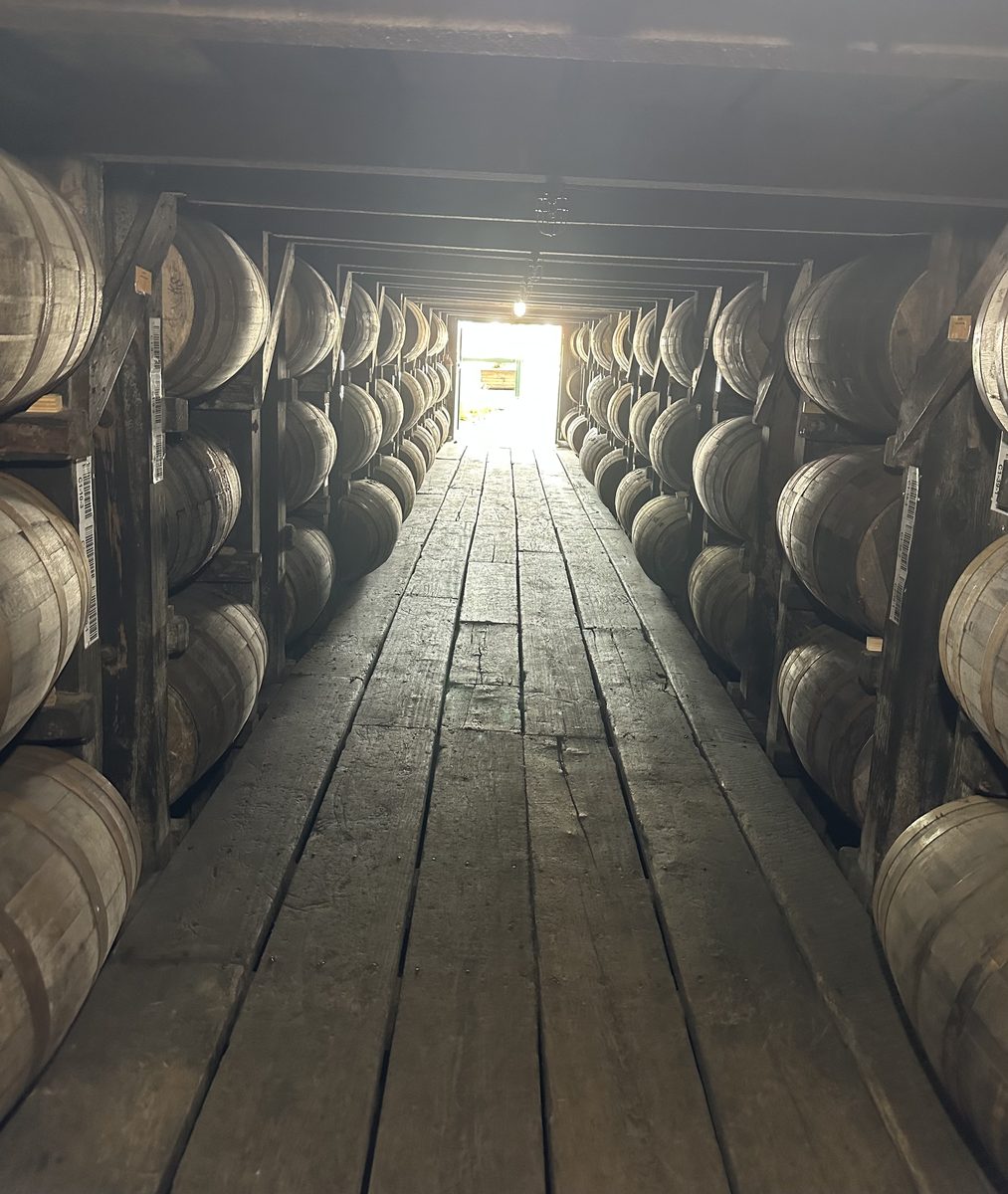 Inside a Buffalo Trace rick house with barrels lining both sides and light at the end