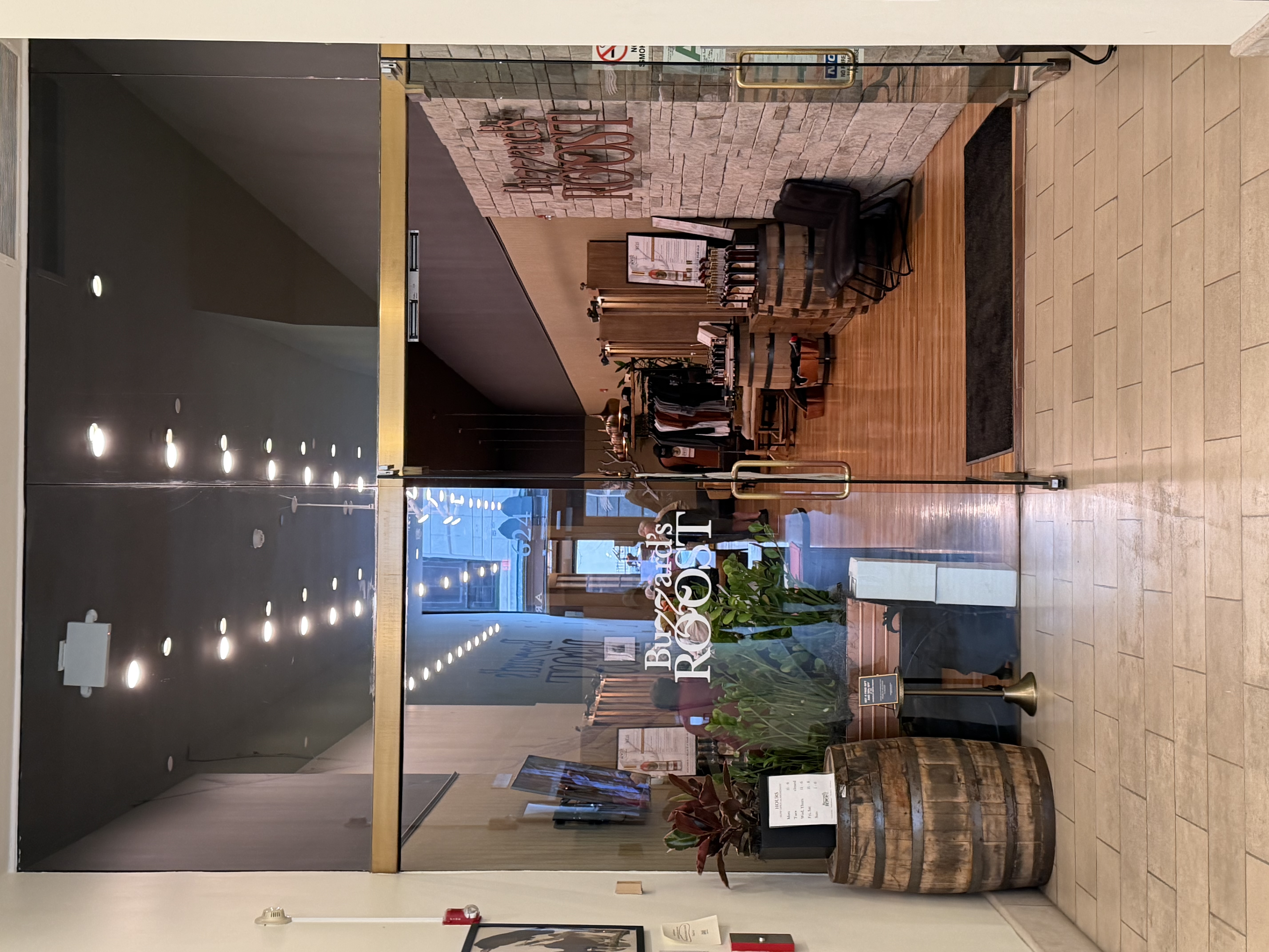 Buzzard's Roost Distillery entrance on Louisville's Whiskey Row, with logo on glass doors and barrels visible inside