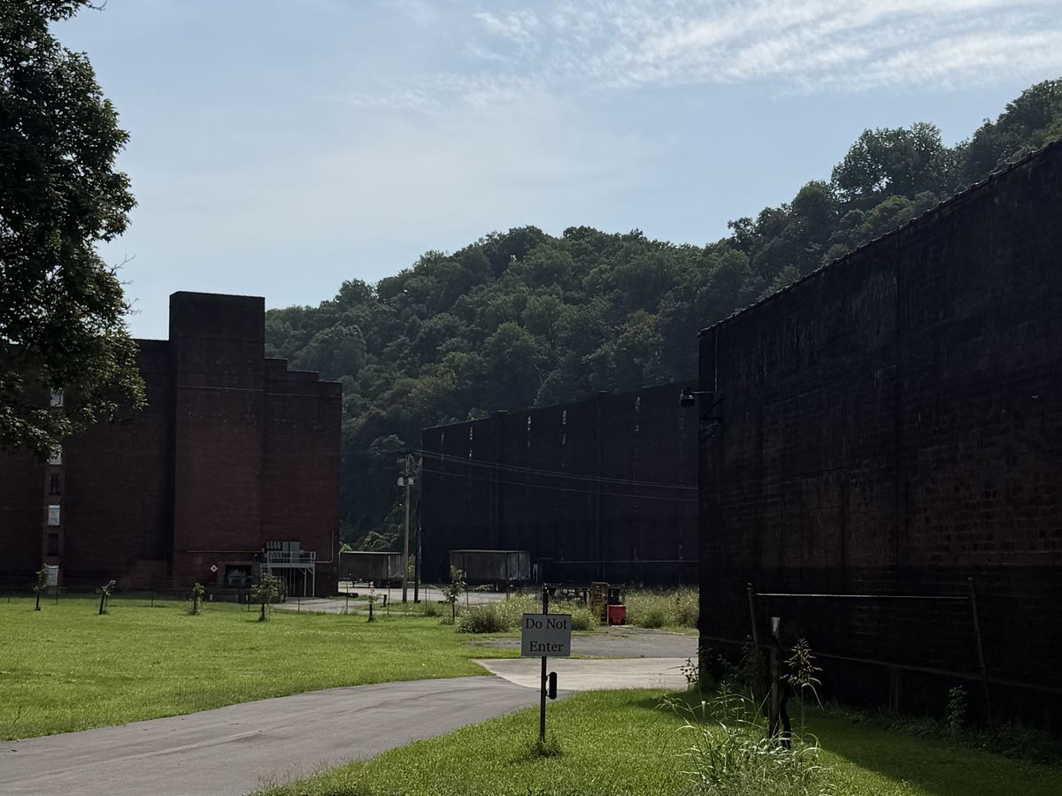 The former Old Crow distillery campus with long stone warehouse buildings and a gravel road