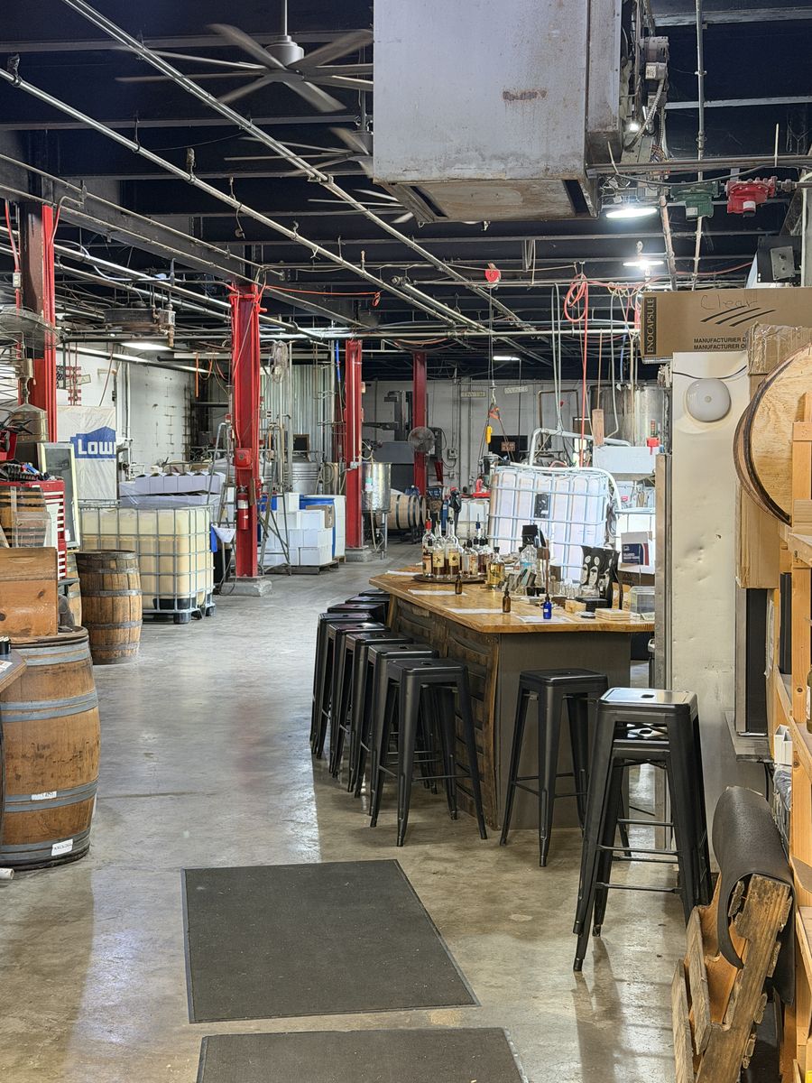 Glenns Creek tasting bar with stools and barrels set among working distillery equipment