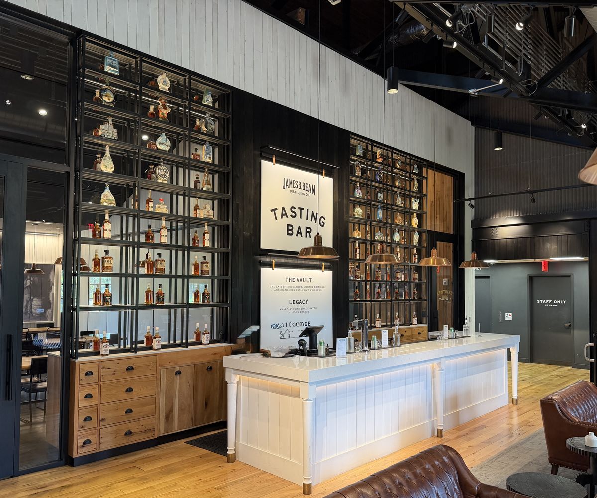 Jim Beam tasting bar with a lit counter and shelves of bottles and glassware behind it