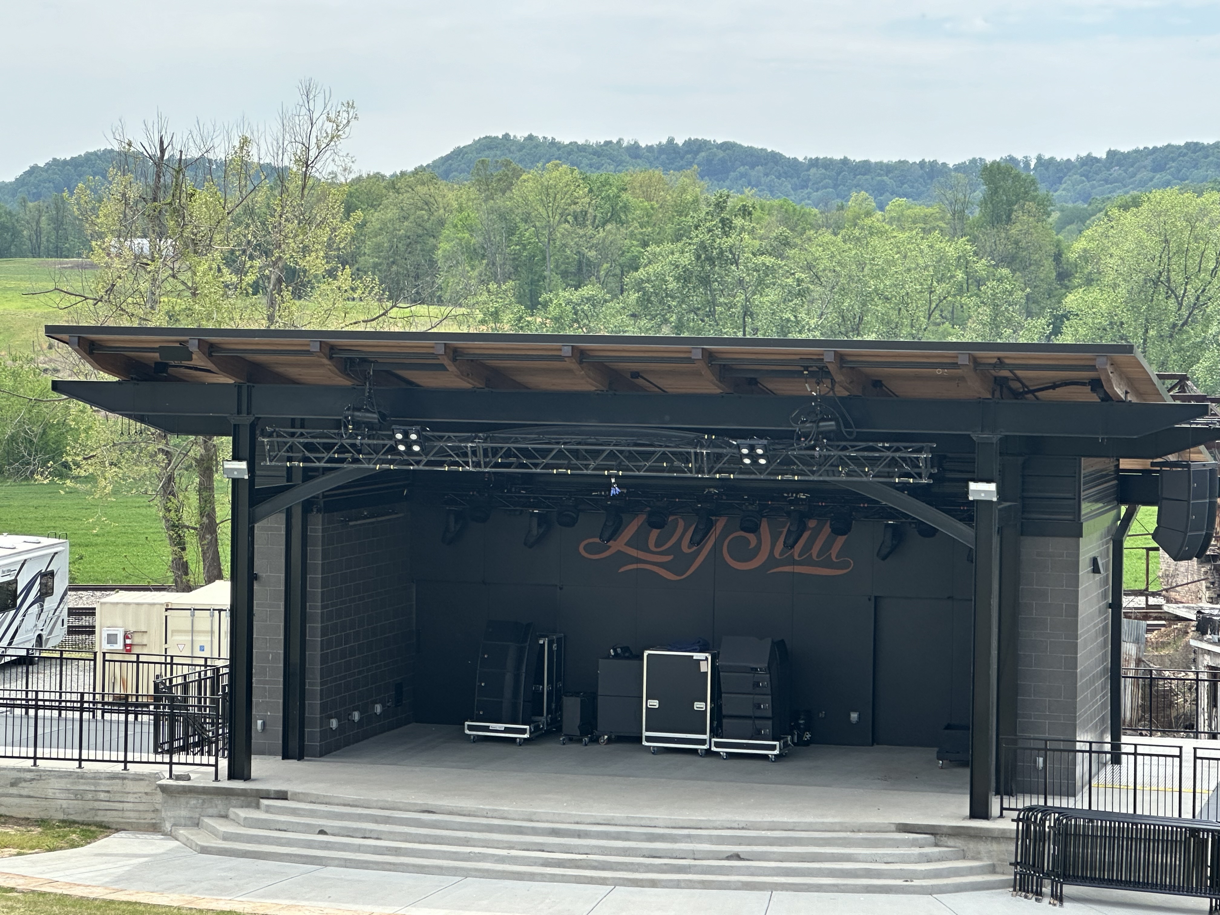 The Amp outdoor concert venue at Log Still Distillery with green Kentucky hills in the background