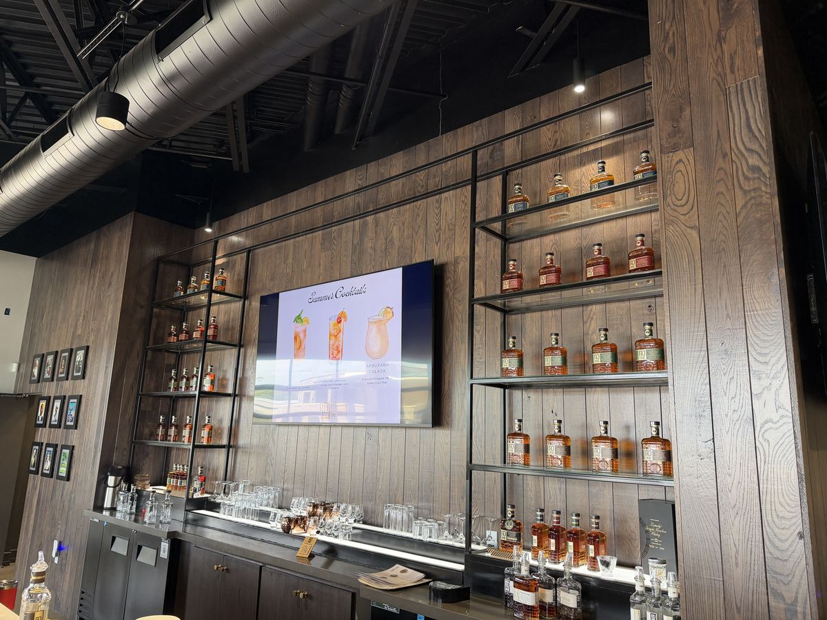 RD1 Spirits bar with bottle shelves and a screen showing the whiskey lineup