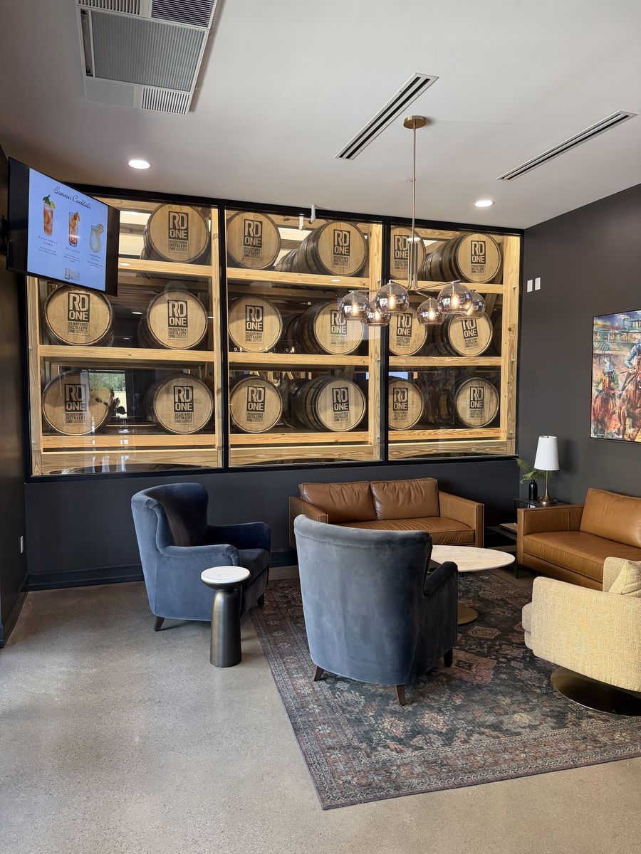 RD1 Spirits lounge with barrels set into a display wall and armchairs around a rug