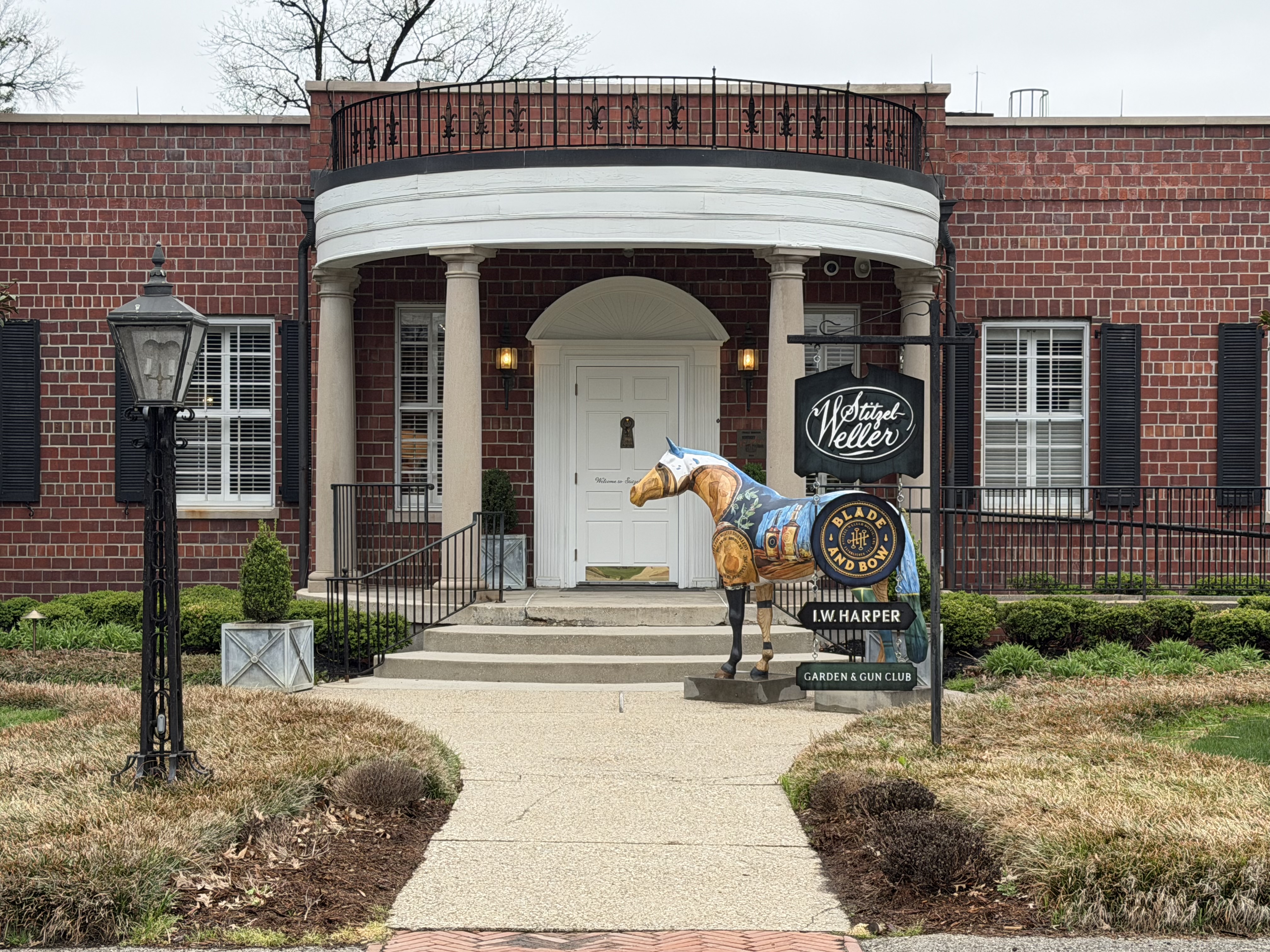 Historic Stitzel-Weller main entrance with white columns, Stitzel-Weller sign, and painted horse statue representing I.W. Harper