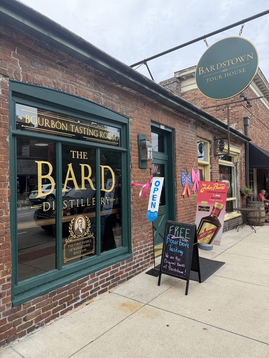 The Bard Distillery tasting room storefront on North Third Street in Bardstown with gold lettering on green trim