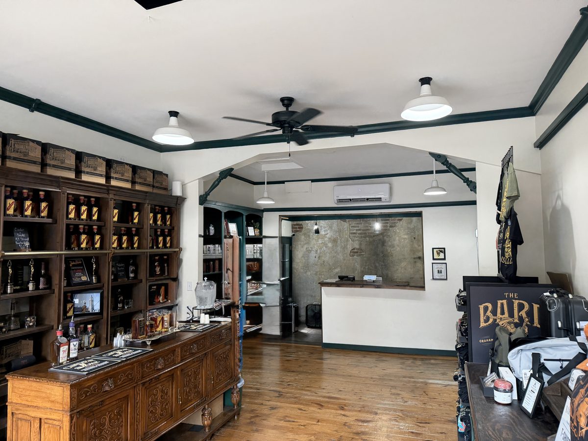 Interior of The Bard tasting room with hardwood floors, an antique sideboard bar and shelves of bottles