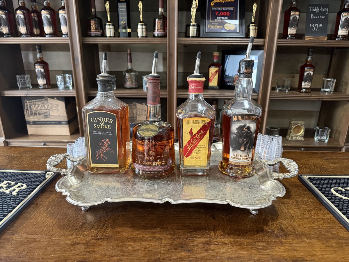 Tasting tray with Cinder and Smoke, Cinder and Smoke Oloroso, Muhlenberg You Got Gold and Muhlenberg bourbon bottles