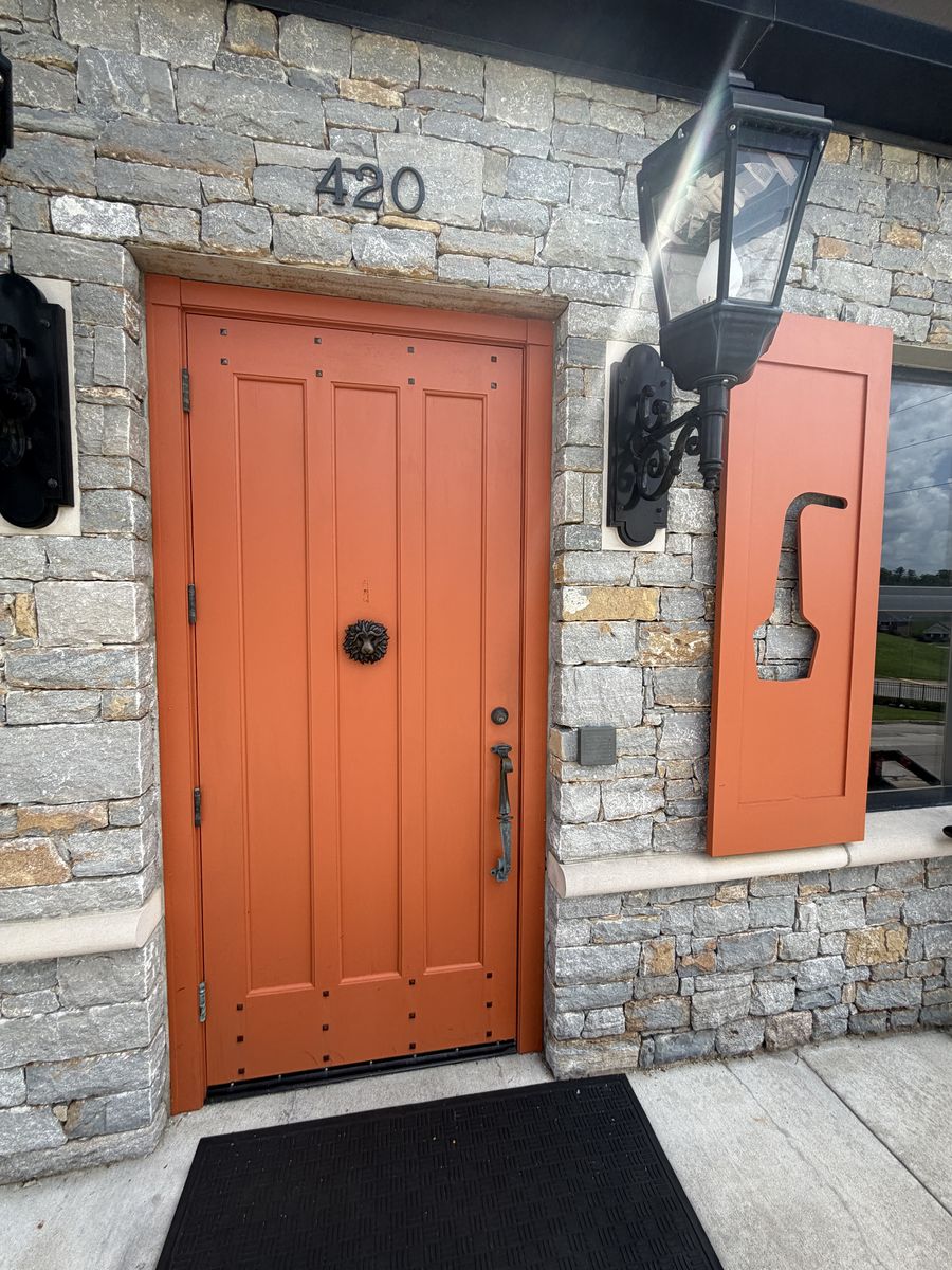 Orange wooden door set into a limestone wall at the Town Branch distillery entrance