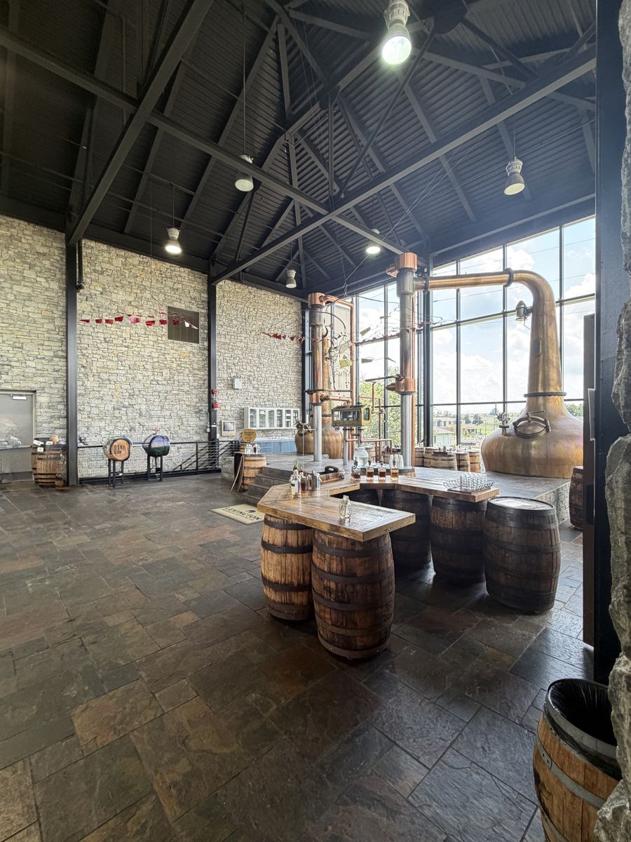 Town Branch still house with copper pot stills behind glass and barrels on a slate floor