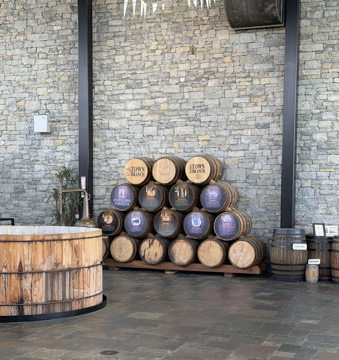 Barrels stacked against a limestone wall beside a wooden fermenter at Town Branch