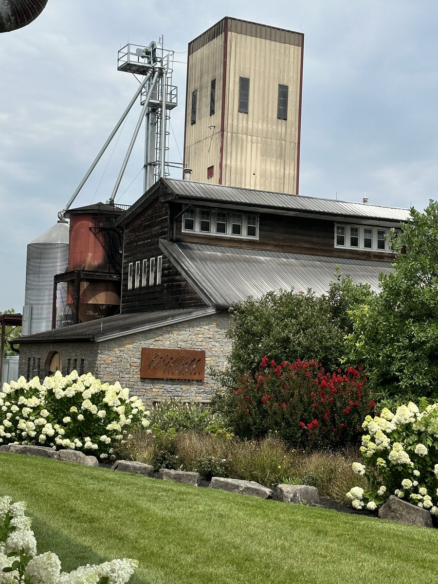 Willett Distillery exterior with stone facade, hydrangeas, and grain tower